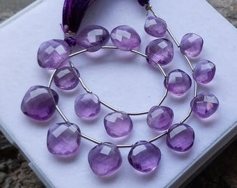 May include: Two strands of faceted amethyst gemstone beads. The beads are a deep purple colour and are strung on silver wire. The strands are arranged on a white surface, with a purple tassel at the top.