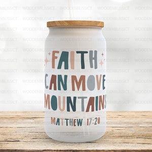 Puede incluir: Un vaso blanco con tapa de madera y un dise&ntilde;o colorido que dice "La fe puede mover monta&ntilde;as" con la referencia b&iacute;blica "Mateo 17:20".