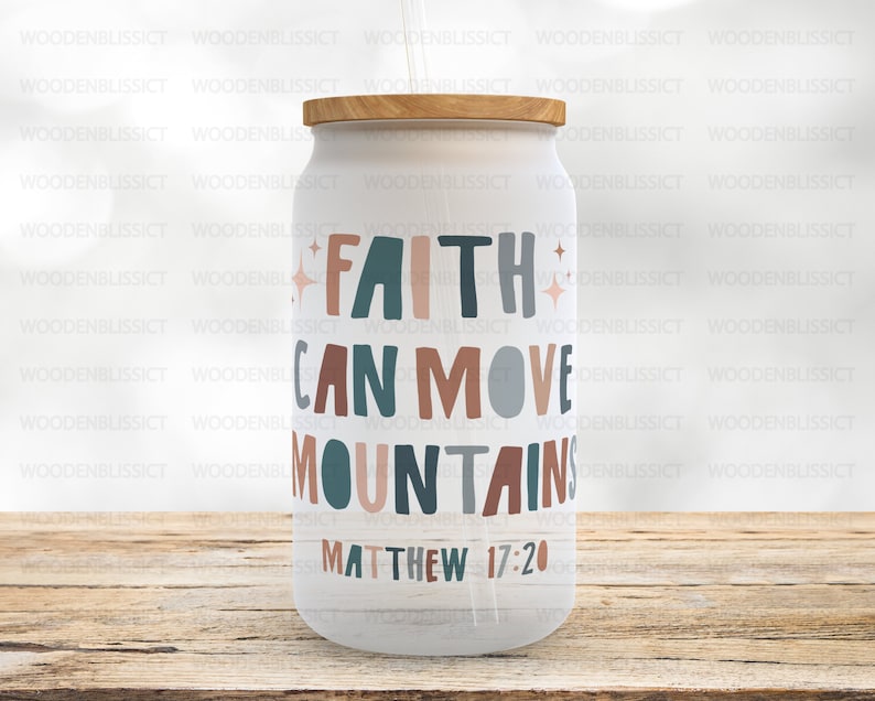 Puede incluir: Un vaso blanco con tapa de madera y un dise&ntilde;o colorido que dice "La fe puede mover monta&ntilde;as" con la referencia b&iacute;blica "Mateo 17:20".