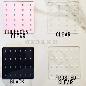 May include: Four earring display boards with different colors and finishes: iridescent clear, clear, black, and frosted clear. Each board has a grid of small holes for holding earrings.