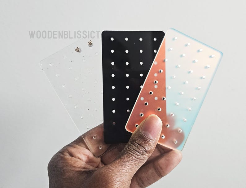May include: Three earring display cards with holes for storing earrings. The cards are clear, black, and iridescent.