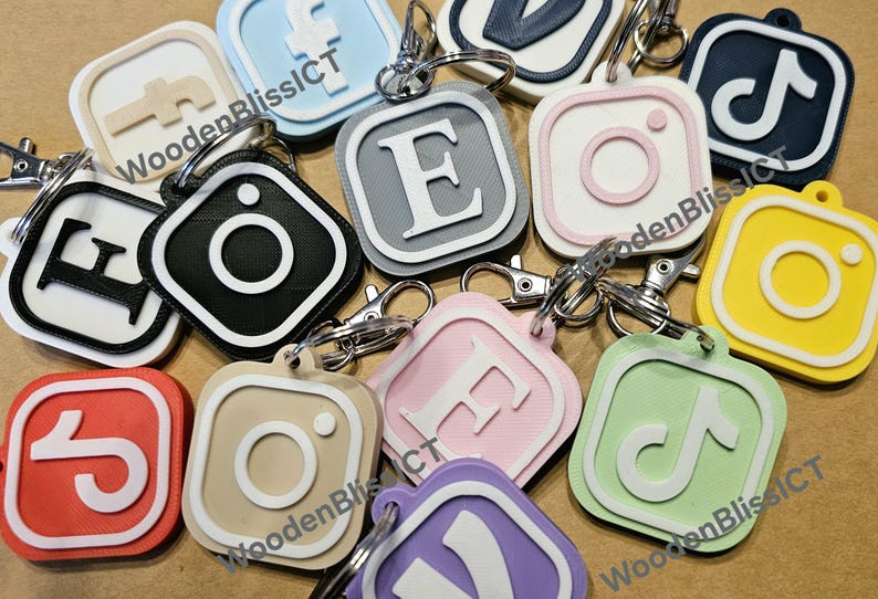Pu&ograve; includere: Una collezione di portachiavi quadrati e colorati con vari loghi e lettere. I portachiavi sono in plastica e hanno un bordo bianco. I loghi includono Instagram, TikTok, Facebook e la lettera E. I portachiavi sono attaccati a anelli portachiavi argentati.