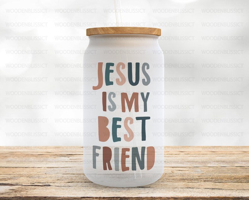 Puede incluir: Un vaso blanco con tapa de madera y una pajita. El vaso tiene el texto "Jes&uacute;s es mi mejor amigo" en letras de colores.