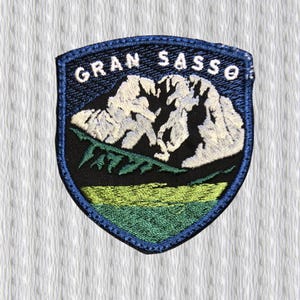 Könnte beinhalten: Gestickter Aufnäher in Schildform mit der Aufschrift "GRAN SASSO" über einer Bergkette. Der Aufnäher hat einen blauen Rand, einen schwarzen Hintergrund und grüne und gelbe Akzente. Zum Aufnähen auf Kleidung.