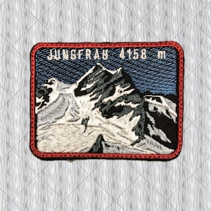May include: A rectangular embroidered patch featuring a mountain landscape with white snow and black rock formations against a blue sky. The text JUNGFRAU 4158 m is stitched in white at the top. The patch has a thick red border around the edge.