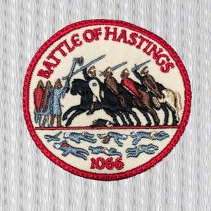 Puede incluir: Parche bordado circular con borde rojo. Representa una escena de batalla histórica con jinetes, soldados caídos y el año 1066. El texto "BATTLE OF HASTINGS" también está presente.