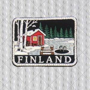 May include: A rectangular embroidered patch featuring a red cabin in a snowy landscape with white birch trees, green pine trees, a wooden dock, and a dark circular ice hole. The word FINLAND is stitched in white capital letters at the bottom.