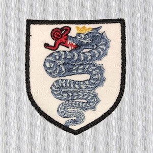 May include: Embroidered patch featuring a blue dragon with a red tongue and accents, wearing a gold crown. The dragon is centered on a white shield with a black border. The patch is likely for clothing or accessories.