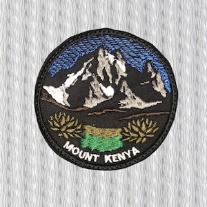 May include: Embroidered patch featuring Mount Kenya. The patch has a black background with a detailed mountain range in white and gray. The sky is blue, and the foreground includes green and gold accents. The text "MOUNT KENYA" is arched along the bottom.