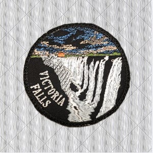 May include: A circular embroidered patch featuring a landscape of Victoria Falls with white cascading water against a black background. The sky above is depicted in shades of blue and orange. The text VICTORIA FALLS is stitched in white.