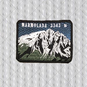May include: A rectangular embroidered patch featuring a mountain landscape with white snow-capped peaks and green slopes against a blue sky. The text MARMOLADA 3343 m is stitched in white across the top of the patch, which has a black border.