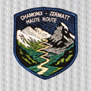 Könnte beinhalten: Gestickter Aufnäher mit einer Berglandschaft mit einem gewundenen Pfad. Der Aufnäher hat einen blauen Rand und den weißen Text "CHAMONIX - ZERMATT HAUTE ROUTE". Das Design umfasst schneebedeckte Berge, grüne Täler und einen blauen Himmel.