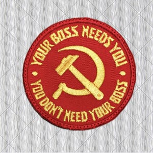 May include: A circular red embroidered patch featuring a yellow hammer and sickle symbol in the centre. The text "YOUR BOSS NEEDS YOU" is stitched in yellow along the top edge, and "YOU DON'T NEED YOUR BOSS" is stitched in yellow along the bottom.