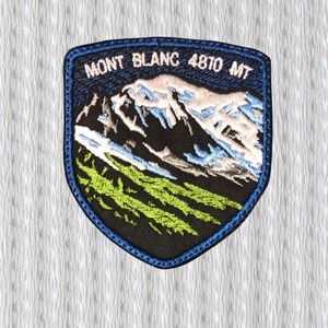 Könnte beinhalten: Gestickter Aufnäher mit blauem Rand, der eine Bergkette mit dem Text "MONT BLANC 4810 MT" darstellt. Der Aufnäher zeigt eine Berglandschaft mit weißen, blauen und grünen Details auf schwarzem Hintergrund.