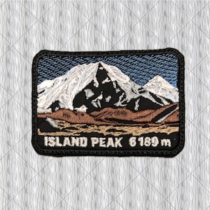 Puede incluir: Un parche rectangular bordado que muestra un paisaje de montaña con picos blancos nevados, laderas rocosas oscuras y un primer plano marrón. El texto ISLAND PEAK 6189 m está bordado en blanco sobre un fondo negro.
