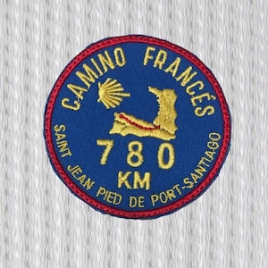 Può includere: Toppa rotonda ricamata in blu, rosso e oro. Il testo recita "CAMINO FRANCES", "SAINT JEAN PIED DE PORT-SANTIAGO" e "780 KM". La toppa presenta una mappa del percorso del Cammino.