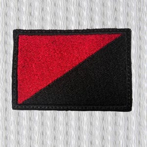 Peut inclure: Écusson brodé avec un motif divisé en diagonale. La section supérieure gauche est rouge et la section inférieure droite est noire. L'écusson a une bordure noire et est de forme rectangulaire.