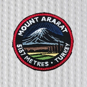 Puede incluir: Parche bordado circular que representa el Monte Ararat, con el texto "MOUNT ARARAT" y "TURKEY". El parche incluye la medida "5137 METRES". El diseño presenta una montaña nevada, un cielo azul y un borde rojo.