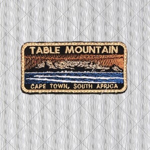 Könnte beinhalten: Gestickter Aufnäher mit dem Tafelberg in Kapstadt, Südafrika. Der rechteckige Aufnäher hat einen schwarzen Hintergrund mit dem Text "TABLE MOUNTAIN" und "CAPE TOWN, SOUTH AFRICA". Das Bild zeigt eine Bergkette, blaues Wasser und einen orange-braunen Himmel.
