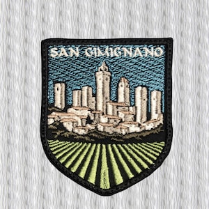 Könnte beinhalten: Gestickter Aufnäher mit der italienischen Stadt San Gimignano. Der Aufnäher zeigt die Skyline der Stadt mit ihren berühmten Türmen vor blauem Himmel. Der untere Teil des Aufnähers zeigt ein Feld aus grünen und gelben Linien.