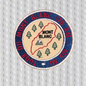 Könnte beinhalten: Runder, gestickter Aufnäher mit blauem Rand, der die Aufschrift "MONT BLANC" und "TOUR DU MONT BLANC" trägt. In der Mitte befindet sich eine Karte der Mont-Blanc-Region mit dem Text "MONT BLANC" und "170 KM - 105 MI".