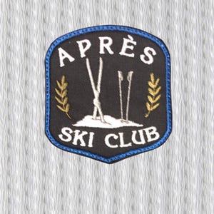 May include: Embroidered patch with the words "APRÈS SKI CLUB" in white lettering on a black background. The patch has a blue border and features a ski scene with skis and poles. Gold-colored wheat stalks are on either side.