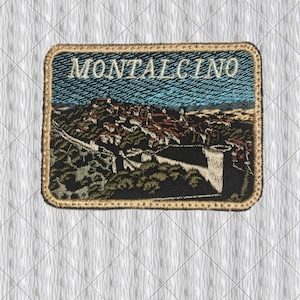 May include: Embroidered patch featuring the word "MONTALCINO" above a detailed landscape scene. The patch has a gold border and depicts a town with red-roofed buildings under a blue sky. The landscape includes trees and a building.