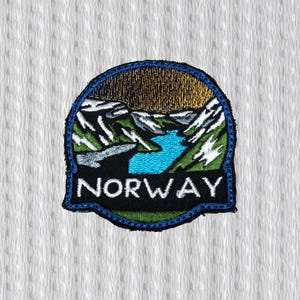 Op de afbeelding: Geborduurde patch met een Noors landschap. De patch heeft een blauwe rand en bevat een turquoise rivier, besneeuwde bergen en het woord "NORWAY" in het wit. Het bovenste gedeelte toont een gouden lucht.
