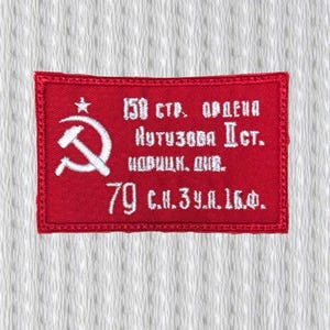 Może przedstawiać: Czerwona prostokątna naszywka z białym haftowanym tekstem i symbolami. Naszywka przedstawia sierp i młot z gwiazdą oraz tekst cyrylicą. Tło to teksturowana biała tkanina.