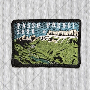 May include: A rectangular embroidered patch featuring a mountain landscape with green slopes, rocky peaks, and a winding path. The text PASSO PORDOI 2239 m is stitched in white against a blue sky background, all enclosed by a thick black border.