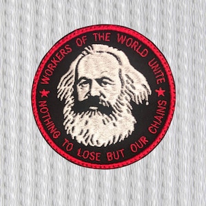 Puede incluir: Parche circular con fondo negro y borde rojo. Presenta un retrato de Karl Marx con cabello y barba blancos. El texto "WORKERS OF THE WORLD UNITE" y "NOTHING TO LOSE BUT OUR CHAINS" está en rojo.