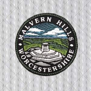 May include: A circular embroidered patch featuring a landscape of the Malvern Hills in Worcestershire. The design shows a stone trig point on a rocky summit, green rolling hills, and a blue sky with white clouds, surrounded by black text.