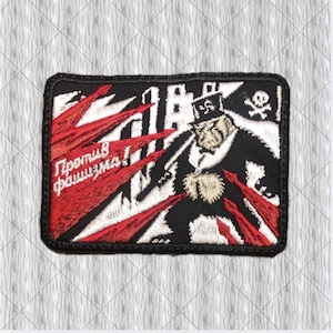 Op de afbeelding: Een rechthoekige geborduurde patch met een zwart, wit en rood ontwerp. Het toont een figuur met een hoge hoed met een hakenkruis, een schedel met gekruiste beenderen en rode speervormige elementen. De cyrillische tekst luidt "Против фашизма!" in het wit.