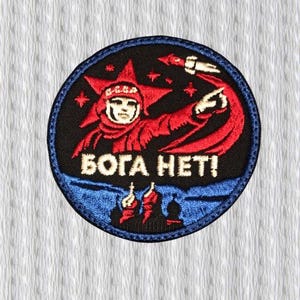 Può includere: Toppa ricamata circolare con una figura rossa con un elmetto a forma di stella che indica un razzo. Il testo bianco "БОГА HET!" è visibile. La toppa ha uno sfondo nero con un bordo blu.