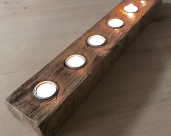 May include: A rustic wooden candle holder with six candle slots. The holder is made of reclaimed wood and has a natural, weathered finish.