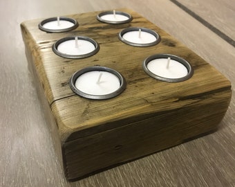 May include: A rustic wooden candle holder with six metal candle cups. The holder is made of reclaimed wood and has a natural, weathered finish.