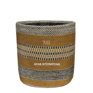 以下が含まれることがあります： ベージュ、黒、クリーム色の織り模様の円筒形バスケット。 バスケットには水平ストライプと「MI」と「MOHIL INTERNATIONAL」の文字があります。
