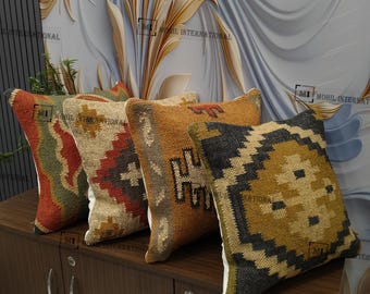 May include: A collection of five decorative throw pillows with geometric patterns. The pillows feature a variety of colors, including red, green, brown, and gold. The pillows are made of a textured material and are arranged on a wooden surface.