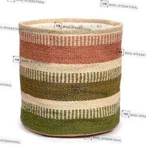 Może przedstawiać: Cylindryczny kosz tkany z poziomymi paskami w odcieniach beżu, pomarańczy i zieleni. Kosz ma solidną konstrukcję i neutralne wnętrze. Design jest prosty i rustykalny, odpowiedni do przechowywania lub dekoracji.