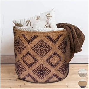 May include: A brown woven storage basket with a geometric pattern in dark brown. The basket is filled with a white pillow and a brown blanket.