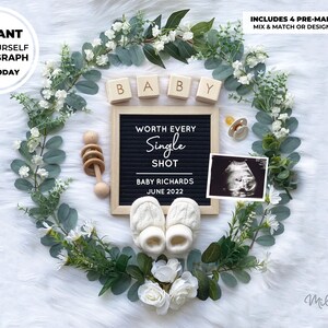May include: A black letter board with the text "WORTH EVERY SINGLE SHOT" and the date "JUNE 2022".  The letter board is surrounded by a wreath of greenery and white flowers.  There are also wooden blocks that spell "BABY", a pacifier, a wooden rattle, and a black and white ultrasound image.
