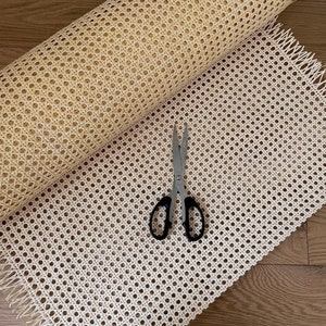 Puede incluir: Un rollo de tejido de mimbre blanco con un par de tijeras sobre una pieza plana de tejido de mimbre blanco.