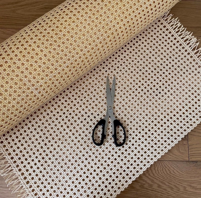 Puede incluir: Un rollo de tejido de mimbre blanco con un par de tijeras sobre una pieza plana de tejido de mimbre blanco.