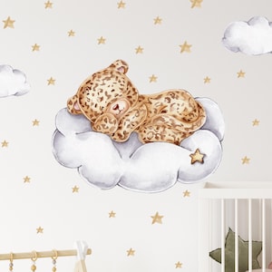 Op de afbeelding: Een aquarel-illustratie van een bruine en gouden luipaard die slaapt op een witte wolk met gouden sterren op een witte achtergrond.