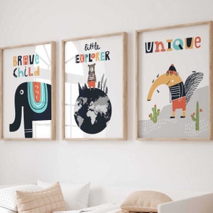 Könnte beinhalten: Drei gerahmte Drucke mit bunten Illustrationen und Text. Der erste Druck zeigt einen blauen Elefanten mit dem Text "Brave Child". Der zweite Druck zeigt einen Bären, der auf einem Globus steht, mit dem Text "Little Explorer". Der dritte Druck zeigt einen Tukan mit dem Text "Unique".