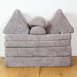 May include: A grey corduroy futon mattress with four foldable sections and two grey corduroy wedge pillows. The futon is folded into a sofa shape.