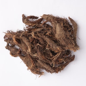 Puede incluir: Un montón de raíces secas, marrones y fibrosas sobre un fondo blanco. Las raíces tienen una apariencia enmarañada y texturizada, con diversas tonalidades de marrón y una textura ligeramente áspera. La imagen está bien iluminada, resaltando los detalles de las raíces.