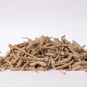 May include: A pile of dried, light brown ashwagandha roots. The roots are of varying lengths and thicknesses, with a rough, textured appearance. The image is set against a plain white background, highlighting the natural color and form of the roots.