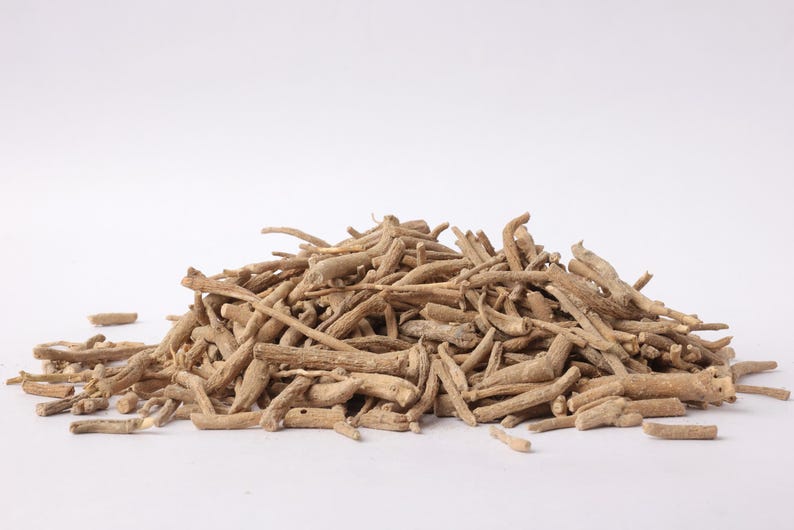 May include: A pile of dried, light brown ashwagandha roots. The roots are of varying lengths and thicknesses, with a rough, textured appearance. The image is set against a plain white background, highlighting the natural color and form of the roots.