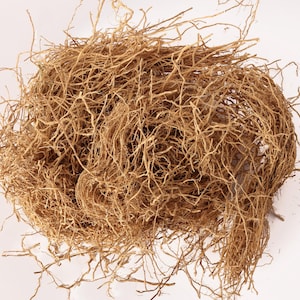 May include: A tangled mass of dried, light brown roots, possibly from a plant, against a white background. The roots are thin and wiry, creating a dense, textured appearance. The overall shape is roughly spherical, with some roots extending outwards.
